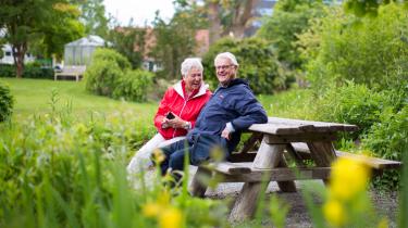 Twee oudere mensen zitten lachend op een bankje